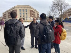 A group of people stands outside on the Michigan campus.