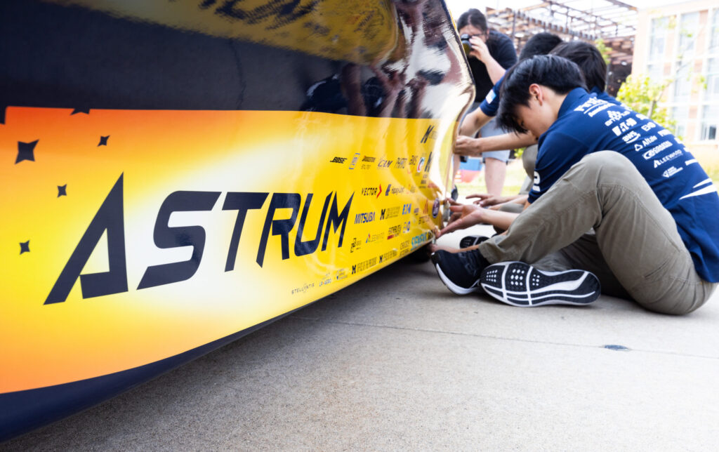 Ethan Lei, mechanical engineer for the 2023 Michigan Solar Car Team, works on the side of Astrum. Image credit: Jeremy Little, Michigan Engineering