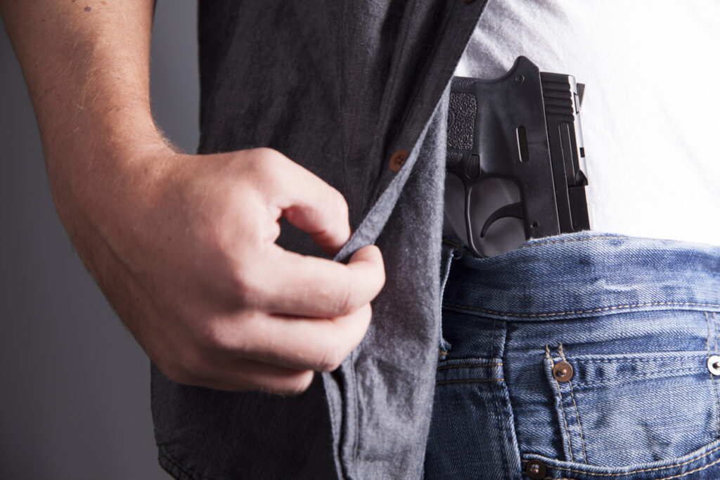 Revealing a firearm tucked into a waistband. Image credit: iStock