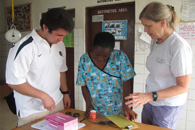 Photo of Jodi Lori, right, and a man (left) helping teach a midwife in Zambia.