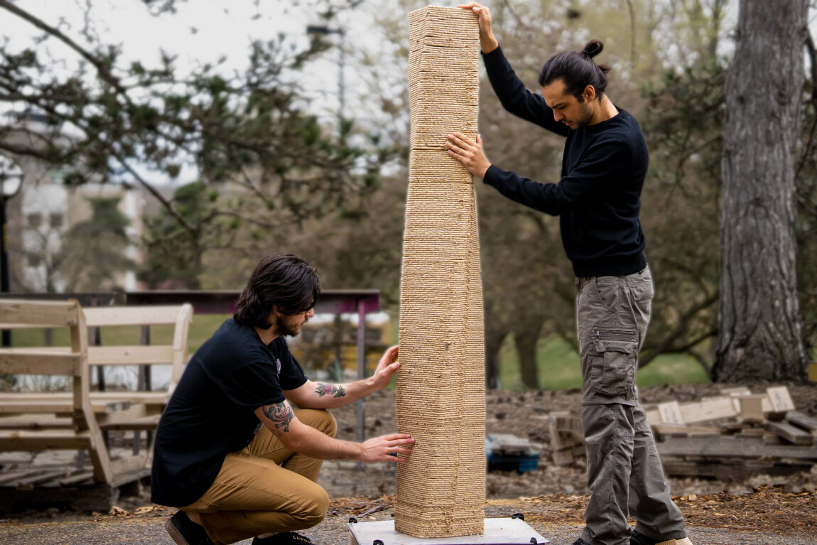 Photo of Zachary Keller and Muhammad Dayyem Khan of the Digital Architecture Research & Technology Laboratory working with robotic 3D-printed, wood-based material paired with incremental set-on-demand concrete casting to create zero-waste freeform concrete structures.