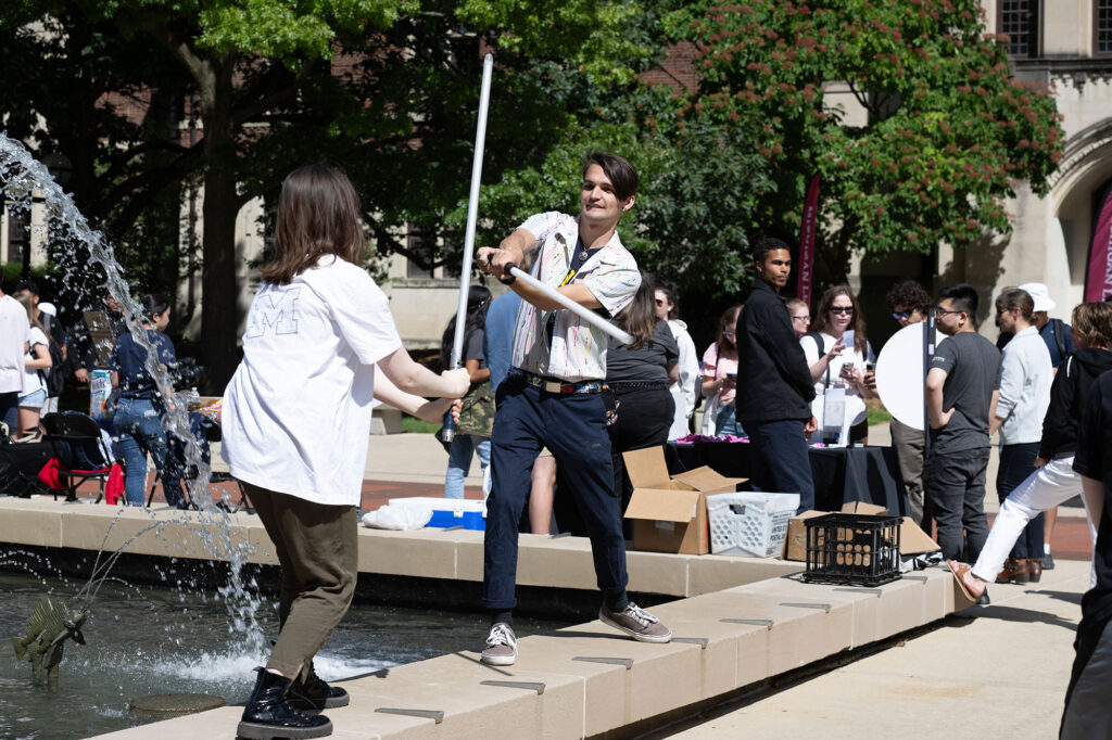 Photo of a man and a woman conducting a light saber battle at Festifall