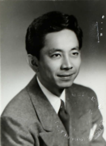 Black & white headshot of young Japanese man wearing a suit and tie.