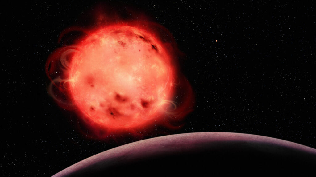 This artistic representation of the TRAPPIST-1 red dwarf star showcases its very active nature. The star appears to have many stellar spots (colder regions of its surface, similar to sunspots) and flares. The exoplanet TRAPPIST-1 b, the closest planet to the system’s central star, can be seen in the foreground with no apparent atmosphere. The exoplanet TRAPPIST-1 g, one of the planets in the system’s habitable zone, can be seen in the background to the right of the star. The TRAPPIST-1 system contains seven Earth-sized exoplanets. Image credit: Benoît Gougeon, Université de Montréal