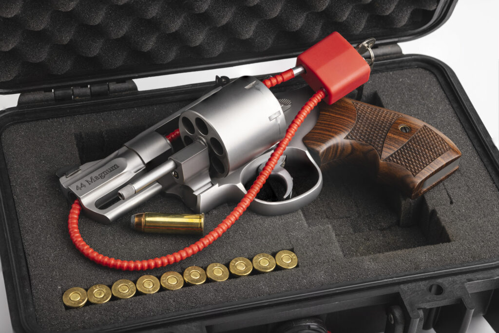 Revolver hand gun with cable key locked and unloaded on case background. Image credit: iStock