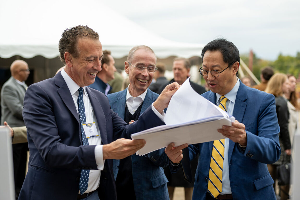 Photo of President Santa J. Ono (right) and others at the ceremony looking over information about the new residential complex.