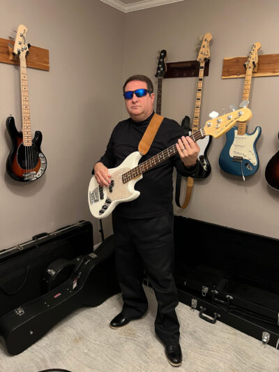 A photo of Gene Mage holding a bass guitar.