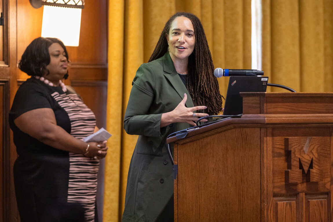 Photo of Tabbye Chavous speaking at a podium while Katrina Wade-Golden looks on.