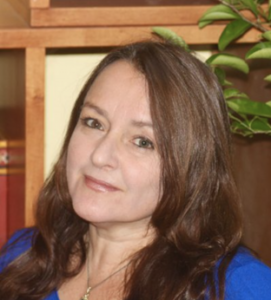 Headshot of a caucasian woman with brown hair and blue shirt.