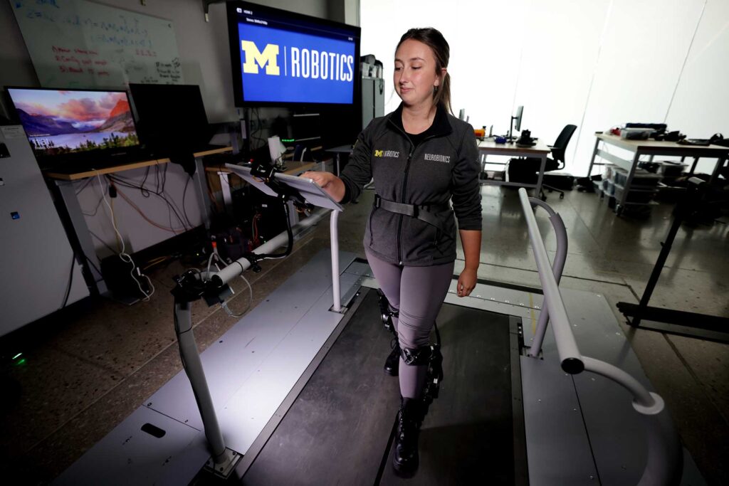 Ellie Wilson, a PhD student in mechanical engineering, demonstrates a new control strategy that customizes assistance provided by a pair of ankle exoskeletons. A machine learning algorithm presents her with two assistance profiles that it has selected based on previous data. She chooses one, and it presents another for comparison. After about 45 choices, most users have found an assistance profile that they choose repeatedly. Image credit: Brenda Ahearn, Michigan Engineering