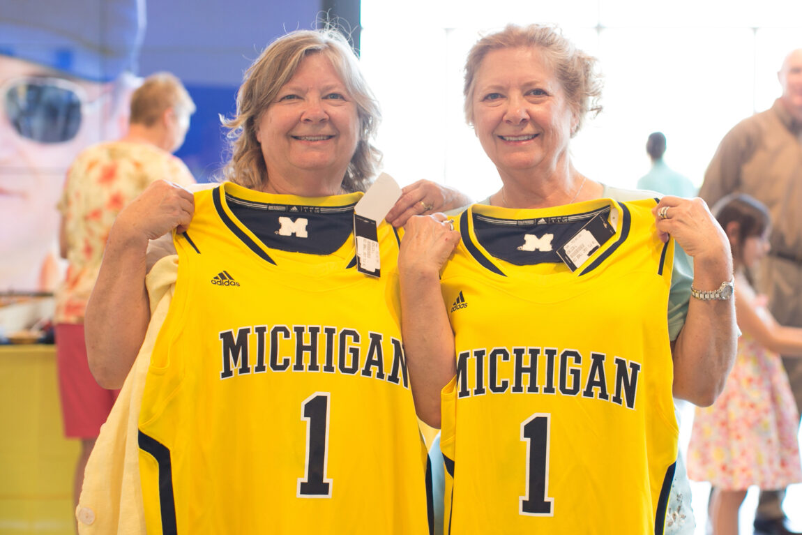 A photo of two twins holding up University of Michigan jerseys