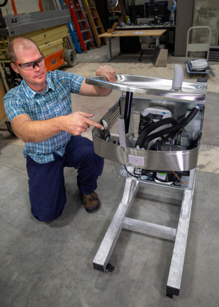Photo of Justin Roelofs with a demonstration water fountain that is used to show public school students in Flint how the water filtration system works.