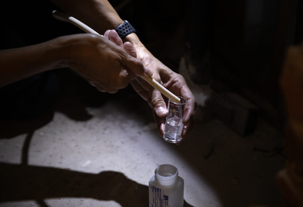 After opening access door and entering the hole in the wall to reach the water supply line behind the water fountain, Nancy Love collects a water sample. Image credit: Marcin Szczepanski, Michigan Engineering
