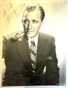 Bing Crosby in sepia photo smoking a pipe. Publicity shot.