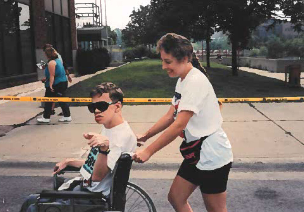 A photo of a woman pushing a man in a wheelchair