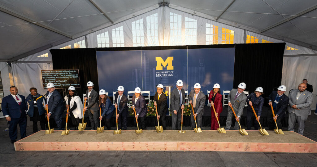 Photo of 16 people in a line breaking ground for the UMCI.