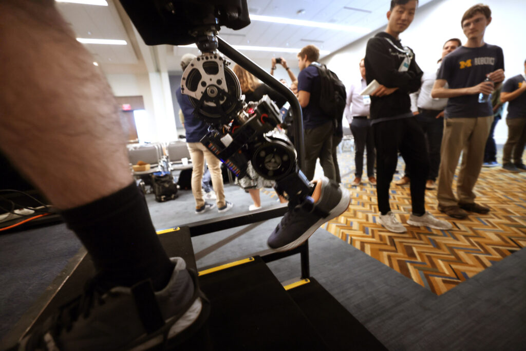 Andrew Seelhoff, left, a first-year PhD student in mechanical engineering at the University of Michigan, demonstrates the robotic prosthetic designed by Robert Gregg’s Locomotor Control Systems Laboratory, at IROS 2023 in October. Image credit: Brenda Ahearn, Michigan Engineering