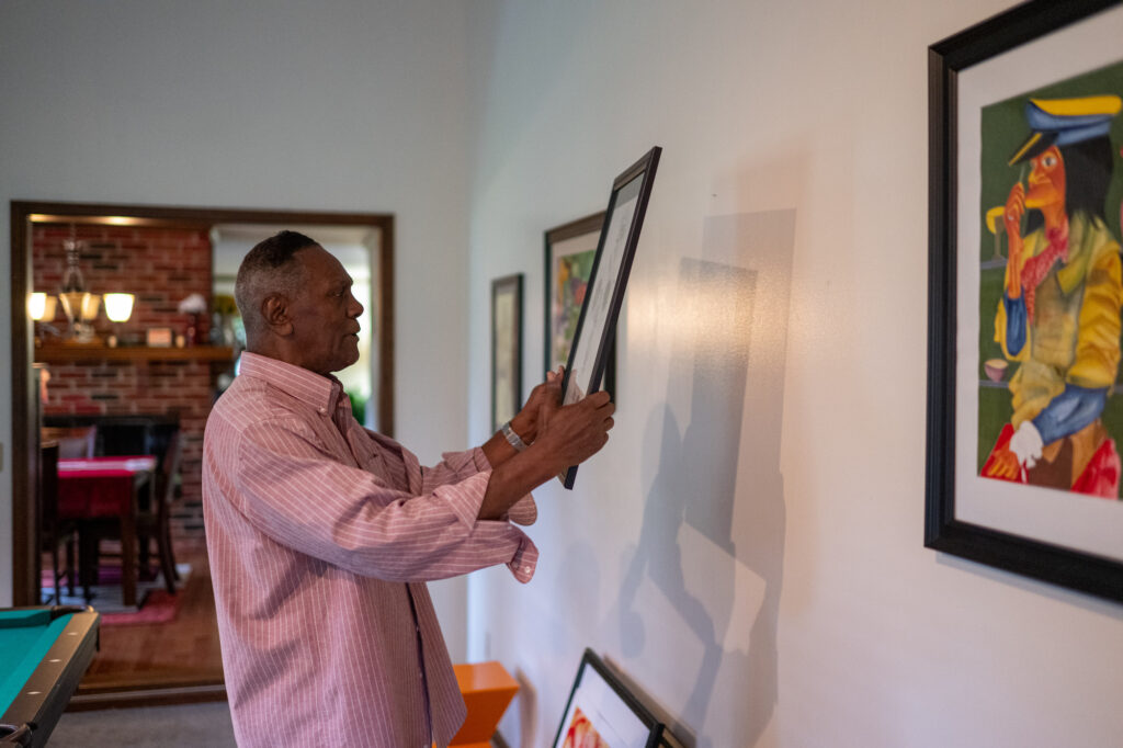 Richard Phillips hangs watercolors he created while incarcerated at his Farmington home. Image credit: Eric Bronson, Michigan Photography