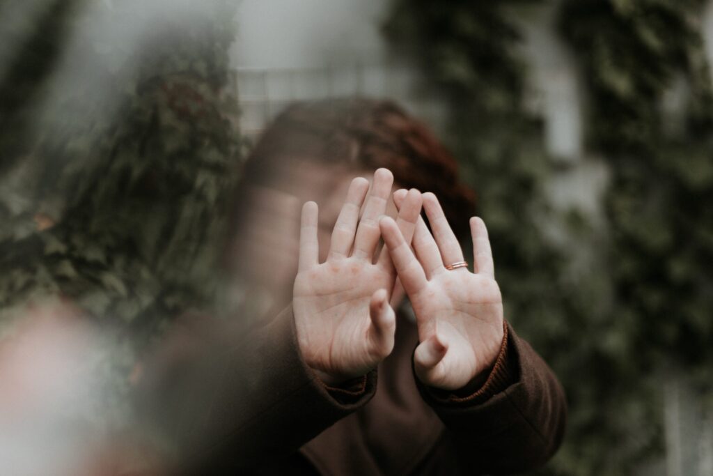 An out of focus woman holds her hands in front of her face. Image credit: Priscilla Du Preez, Unsplash