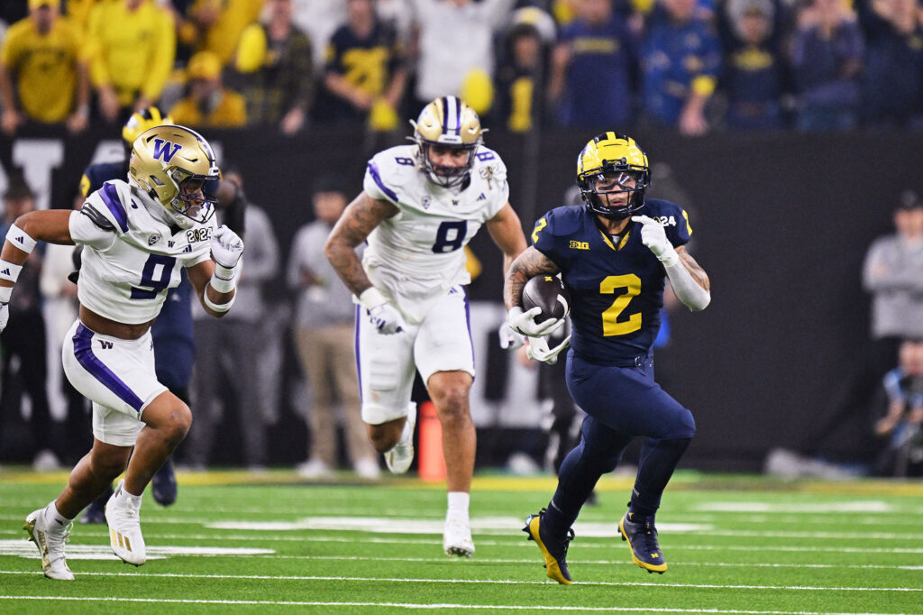 Photo of running back Blake Corum outrunning Washington defenders. 