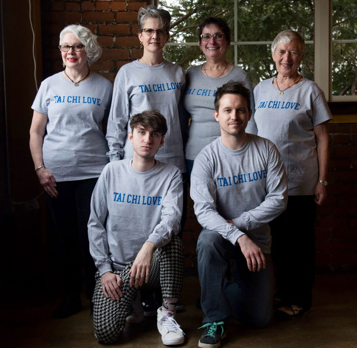 A photo of four women standing and two men kneeling