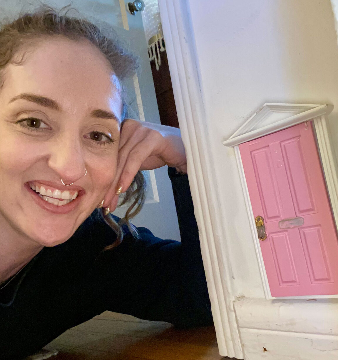 A photo of a woman next to a tiny door