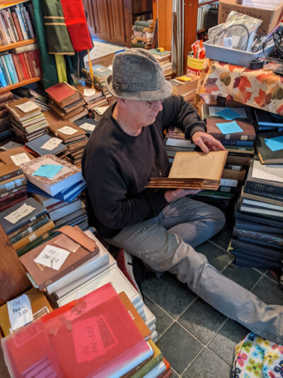 A photo of a man sitting on the floor reading and surrounded by books