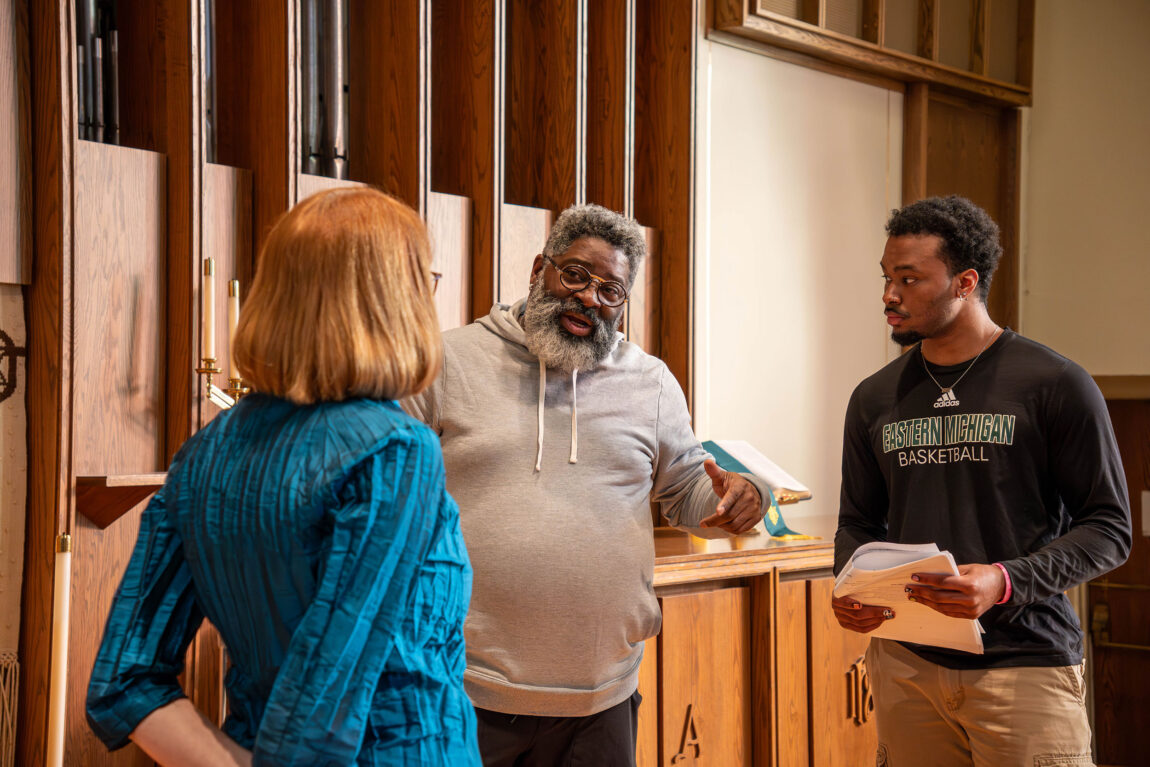 A photo of three people talking about an arts production