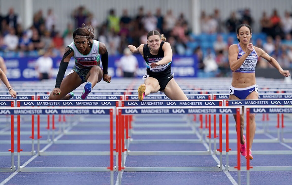 A photo of three women competing in the hurdles