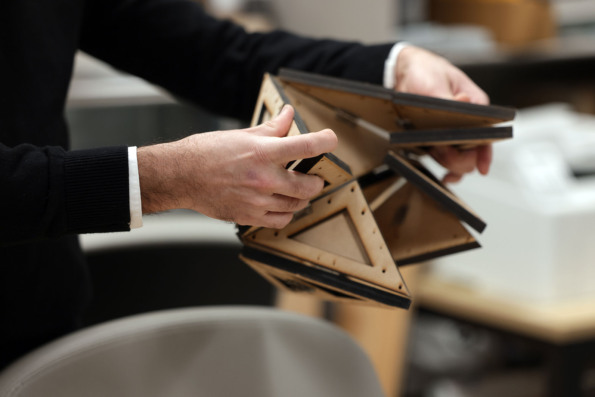 Photo of Evgueni Filipov demonstrating different folds and structures with a small origami model