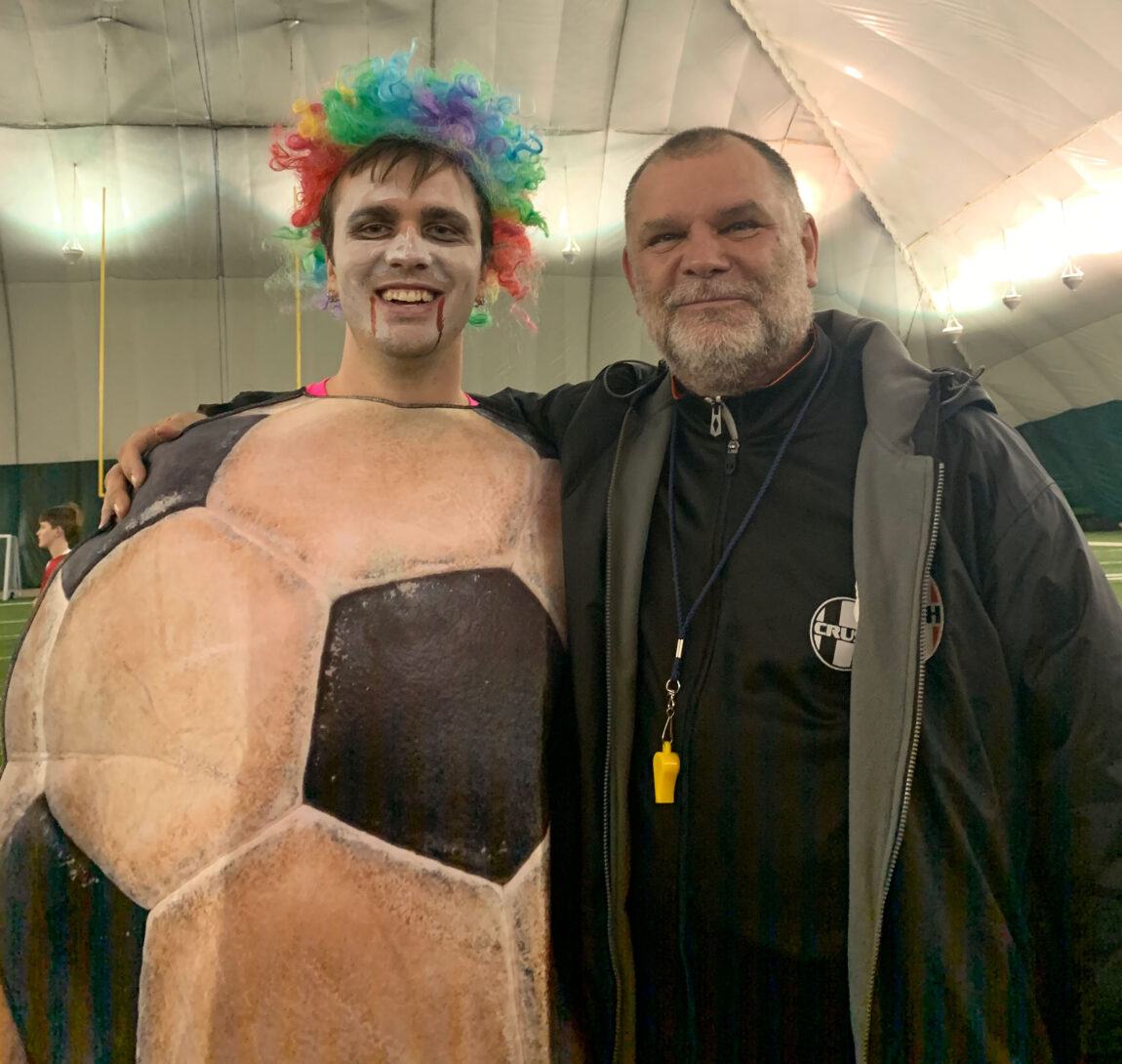 A photo of two men, one dressed as a soccer ball.