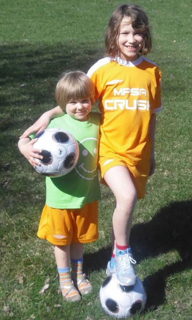 A photo of two girls with two soccer balls