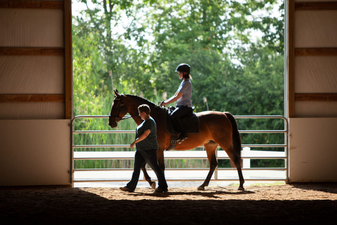 A photo of a person riding a horse while being led by another person.
