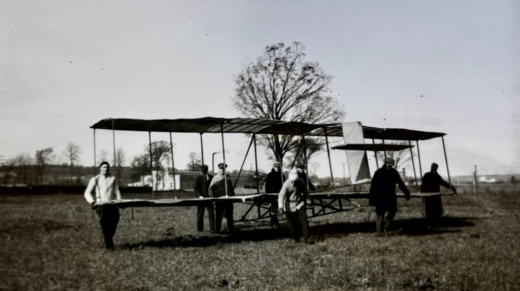 A photo of several students around a glider in 1911