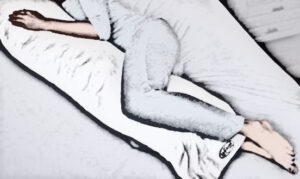 Person lays down with body pillow