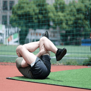 Person on the ground crosses legs and pulls them toward upper body using both hands