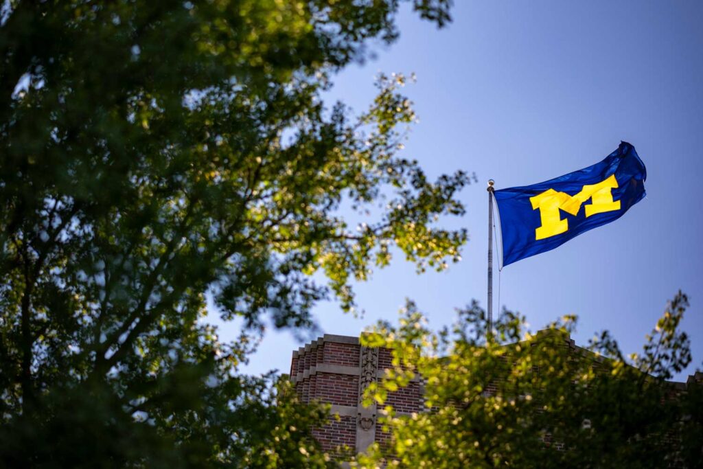 U-M flag flying over campus. Image credit: Michigan Photography