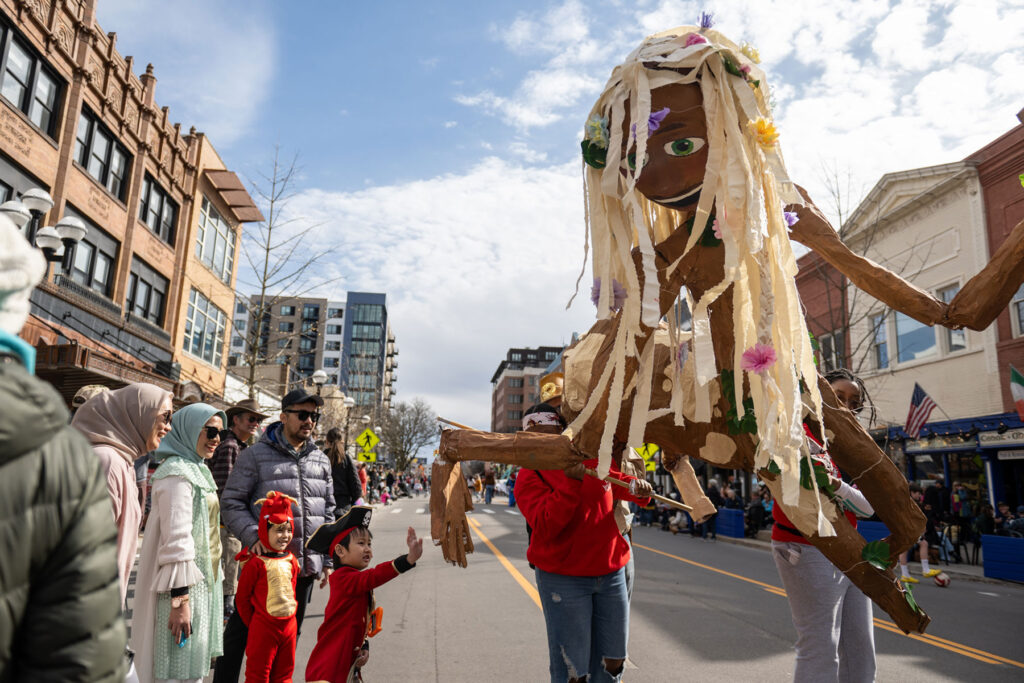 Photo of a small boy in a pirate hat high-fiving a giant puppet