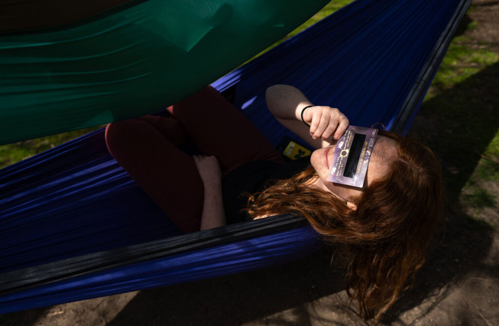 Photo of a student watching the eclipse from a hammock