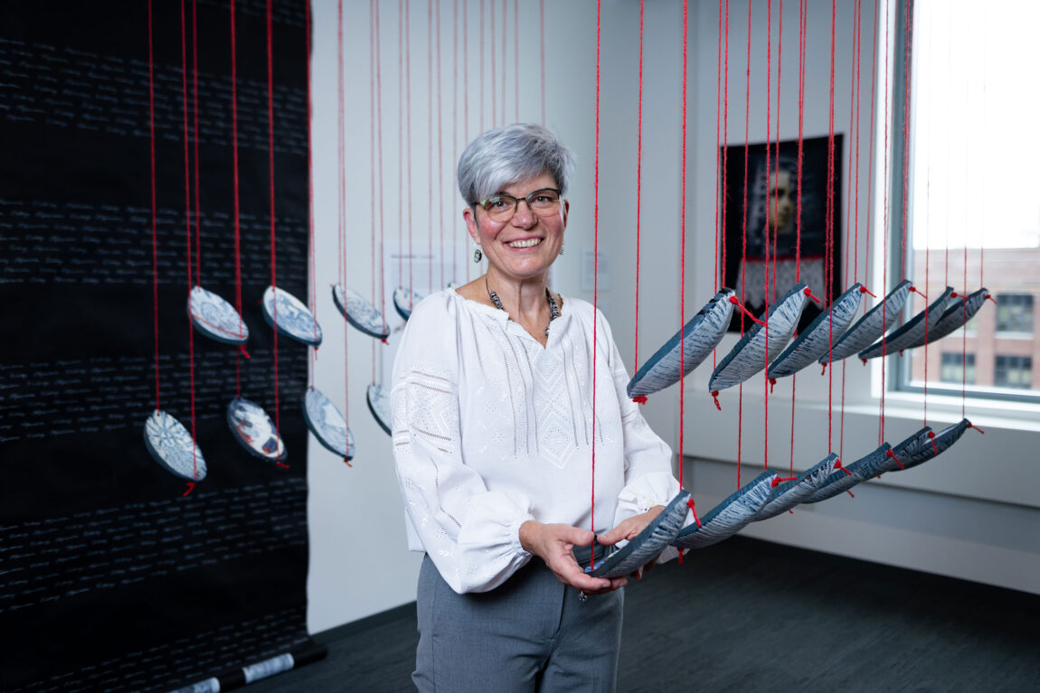 A photo of a woman standing with her art installation