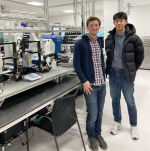 Samuel Cross (left), a former Samsung engineer, stands in front of ASTRAL, Samsung's robotic lab, with co-first author Jiadong Chen (right), the study's computational lead and a doctoral student at U-M. Image credit: Samuel Cross, Advanced Materials Lab, Samsung Advanced Institute of Technology-America, Samsung Semiconductor