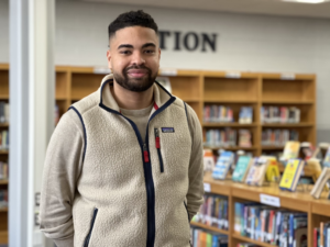 Young bearded male with fleece vest in a library setting. Teacher.