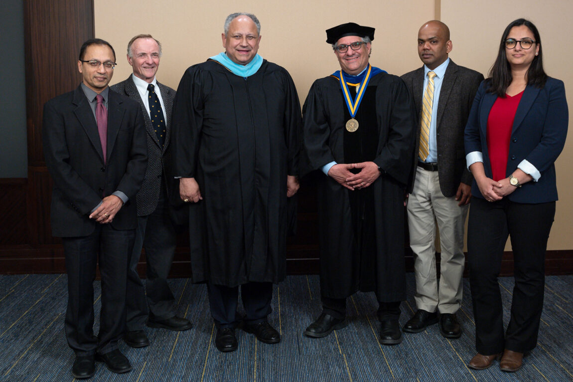 A photo of five men and a woman standing side by side