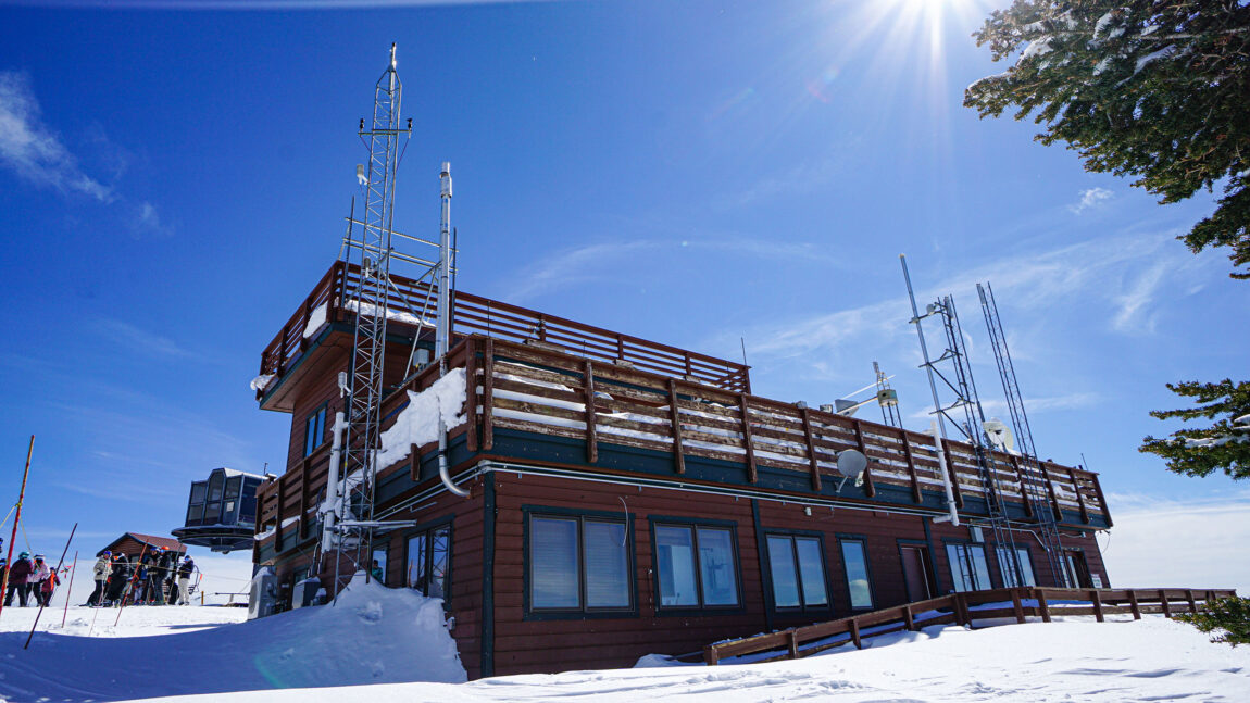 The outside of storm peak lab resembles a cabin at a ski resort, except it has several metal radio towers with instruments that collect data on the properties of clouds and snow.