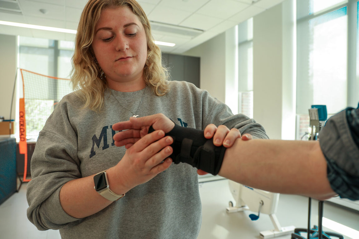 A photo of a woman working with another wearing a wrist brace