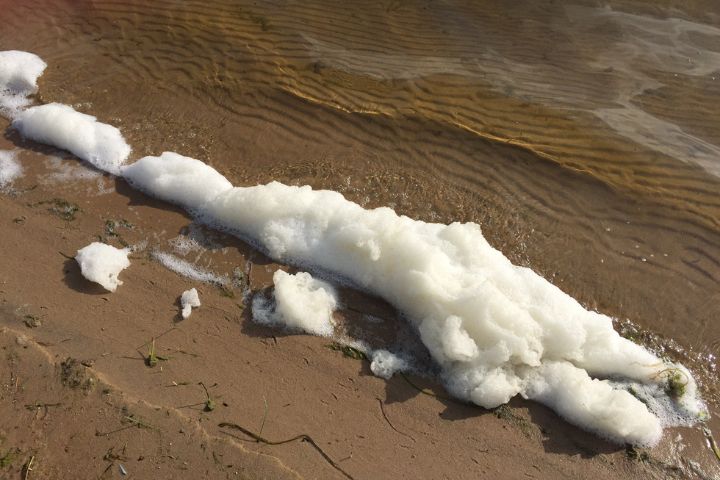 A foam wave breaking upon the sand of a beach. Image credit: Michigan Department of Environment, Great Lakes, and Energy