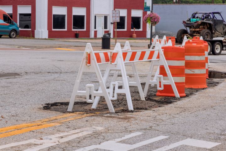 Road covered in potholes that is blocked off by construction bridges and cones. Image courtesy: Graham Sustainability Institute