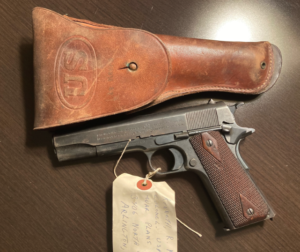 An M1911 handgun with leather case found in Colonel Kenneth Kreps' WWII war chest.