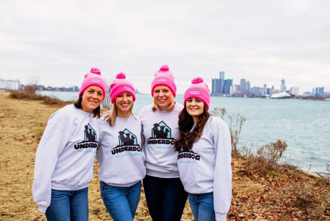 A photo of four women standing by a river