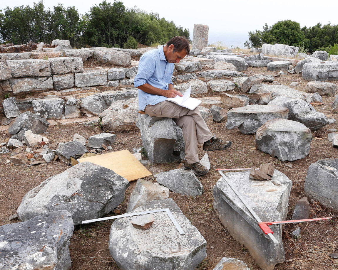 Photo of a man taking notes amid a field of large stones